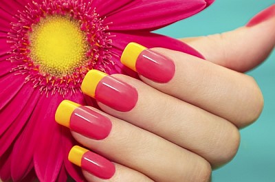 Manicura con barniz rosa y amarillo con flor.