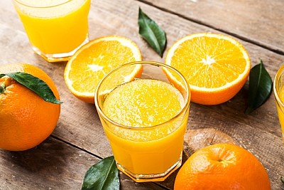 Wyciskany sok pomarańczowy w szklance i świeże pomarańcze