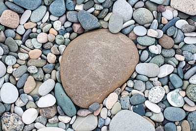 småsten på stranden med en stor sten