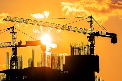 Grues à tour et silhouettes de construction au lever du soleil