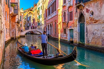 Canal estrecho con góndola y puente en Venecia,