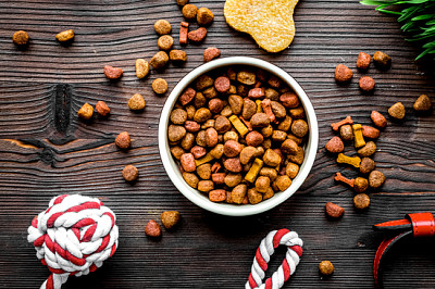 Cibo per cani secco nella ciotola sulla vista superiore del fondo di legno