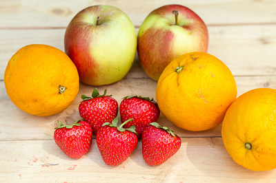 Äpplen, apelsiner och jordgubbar på träbord