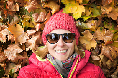 Schöne Frau, die im bunten Herbstlaub liegt