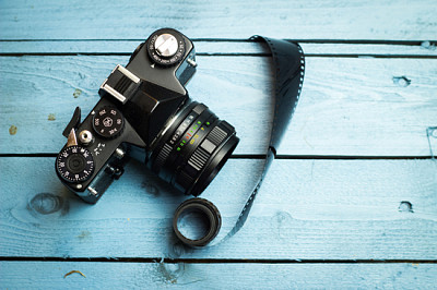 Old film camera, and old film on a blue wooden bac