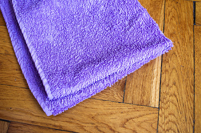 Buntes gebogenes Handtuch auf hölzernem Hintergrund: lila c