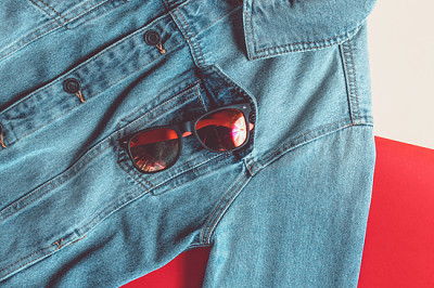 Слънчеви очила в джоб на яке на дънки върху цветно б