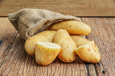 Patatas orgánicas crudas en el saco sobre tablones de madera ba