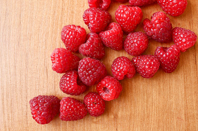 Composition of many raspberries on bright wooden t