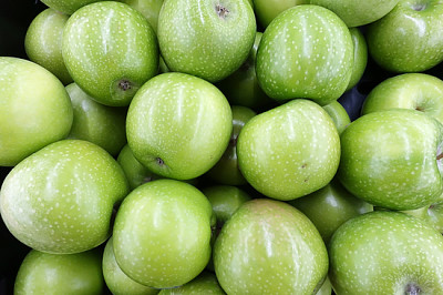 Many ripe juicy green apples in supermarket.