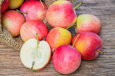 Manzanas frescas con un saco de tela en la mesa de madera