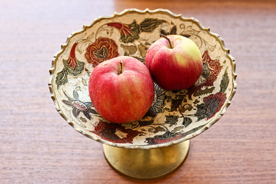 Apples in decorated metallic bowl with flowers orn