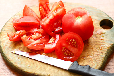 Cortar los tomates y un cuchillo sobre una tabla de madera húmeda.