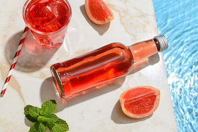 Botella de refresco de pomelo fresco cerca de la piscina