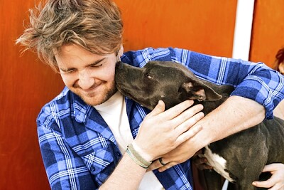 Ein Mann, der von einem entzückenden Hund geleckt wird