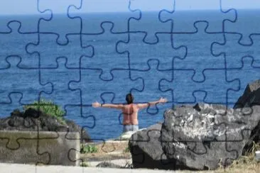Un joven saluda el mar con sus brazos abiertos