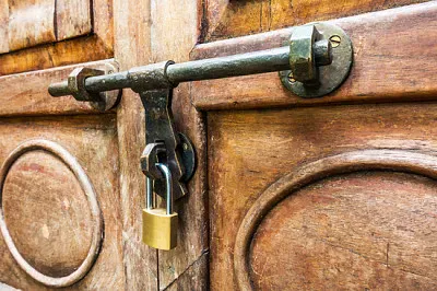 Pestillo antiguo y candado en una puerta de madera