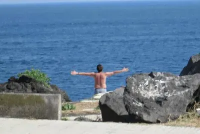 Un joven saluda el mar con sus brazos abiertos