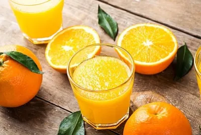 Spremuta d'arancia in un bicchiere e arance fresche