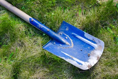 Blaue Schaufel auf einem grünen Gras
