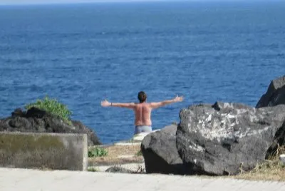Un joven saluda el mar con sus brazos abiertos jigsaw puzzle
